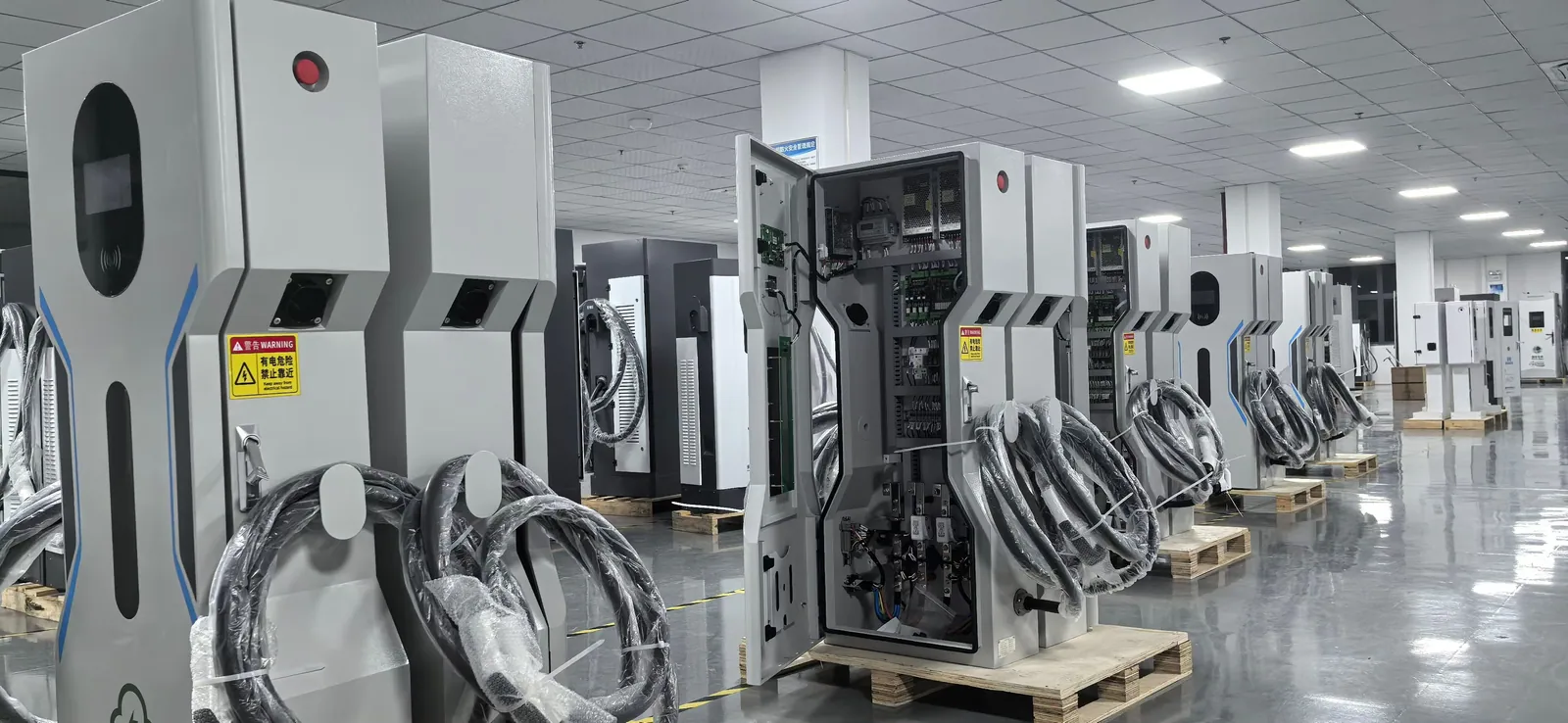 Open EV charger cabinets arranged for internal assembly and inspection in a production workshop